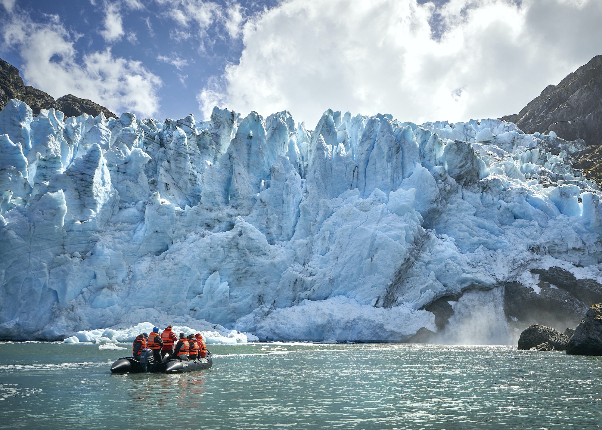 Tourists in a zodiac cruise past ice in front of a glacier in Tierra del Fuego
