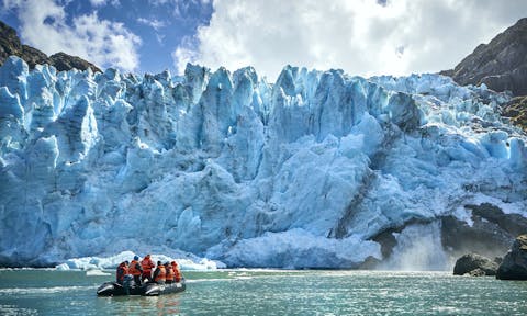 Tourists in a zodiac cruise past ice in front of a glacier in Tierra del Fuego