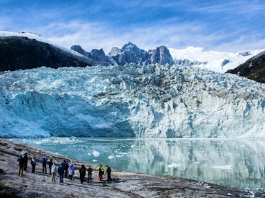Tourists walk on the beach opposite Pia Glacier in Tierra del Fuego on an Australis cruise