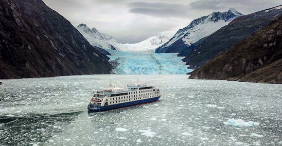 Ventus Australis cruise ship with glacier and mountains in icy waters of Tierra del Fuego