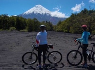 Two mountain bikers looking at the Osorno Volcano in the distance, near Puerto Varas, Chile