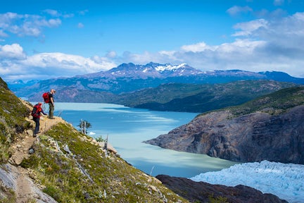 Two hikers standing on a narrow path above Glacier Grey and Grey Lake, Torres del Paine, Patagonia, Chile. Torres del Paine Hike.
