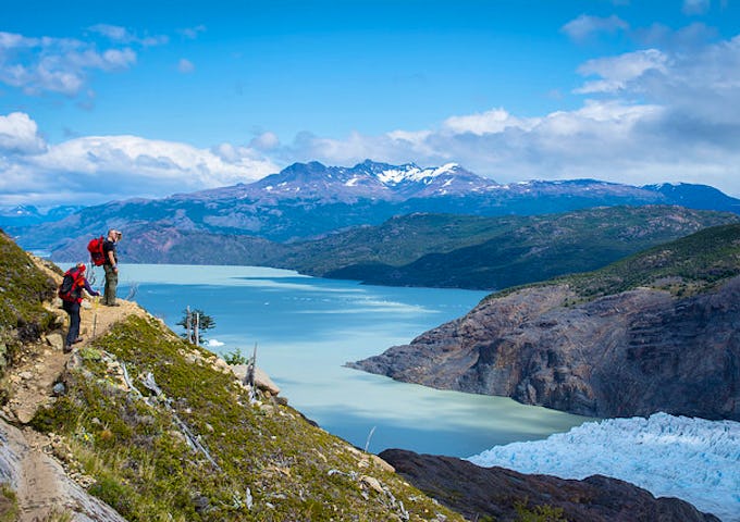 Two hikers standing on a narrow path above Glacier Grey and Grey Lake, Torres del Paine, Patagonia, Chile. Torres del Paine Hike.