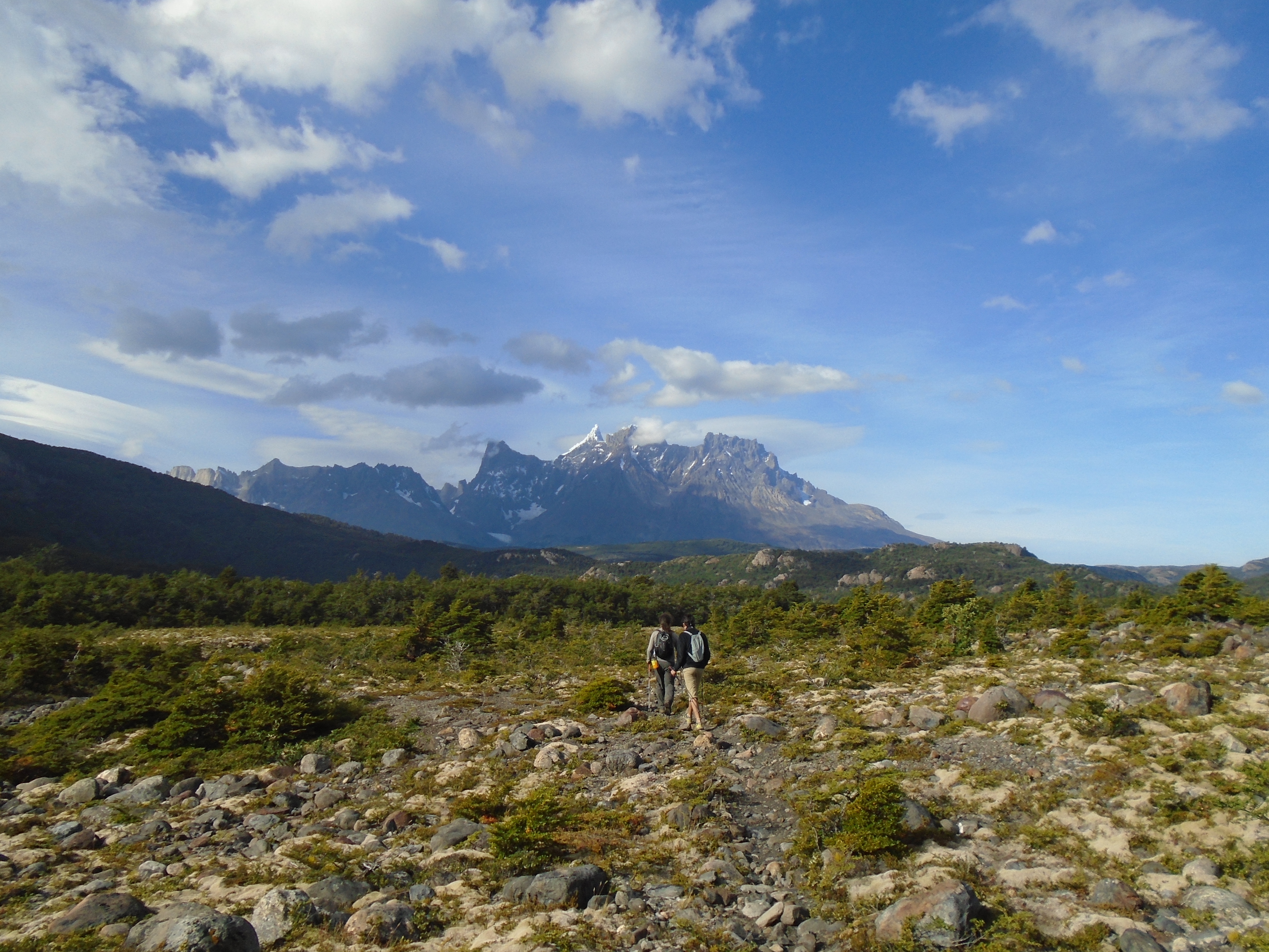 Two hikers walking across rought terrain towards a mountain in the Pingo Valley, Torres del Paine National Park. Torres del Paine Hike, Chile