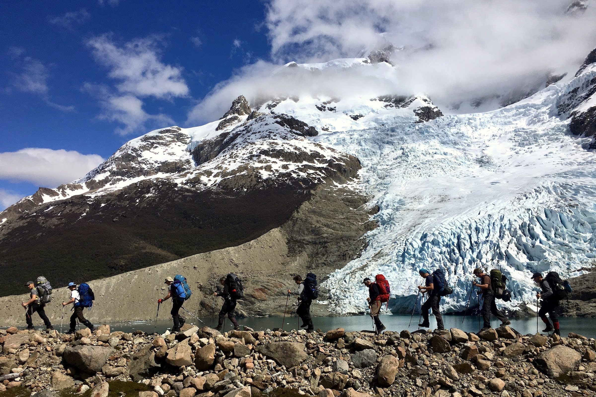 Hikers passing a glacier on the Estancia Helsingfors to Estancia Cristina trek in Los Glaciares