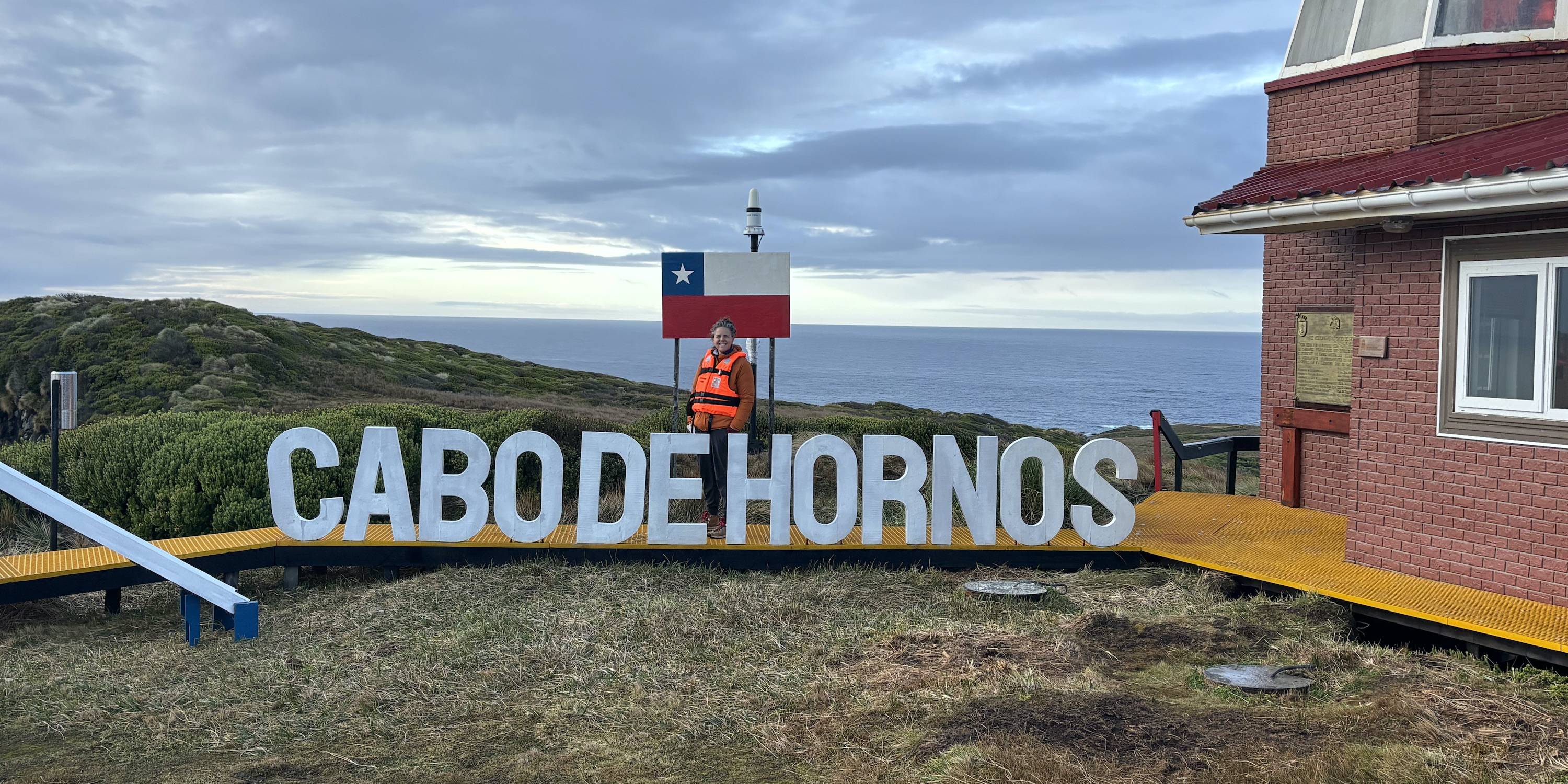 Tourist standing at the Cabo de Hornos sign at Cape Horn