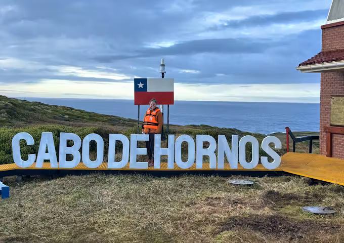 Tourist standing at the Cabo de Hornos sign at Cape Horn
