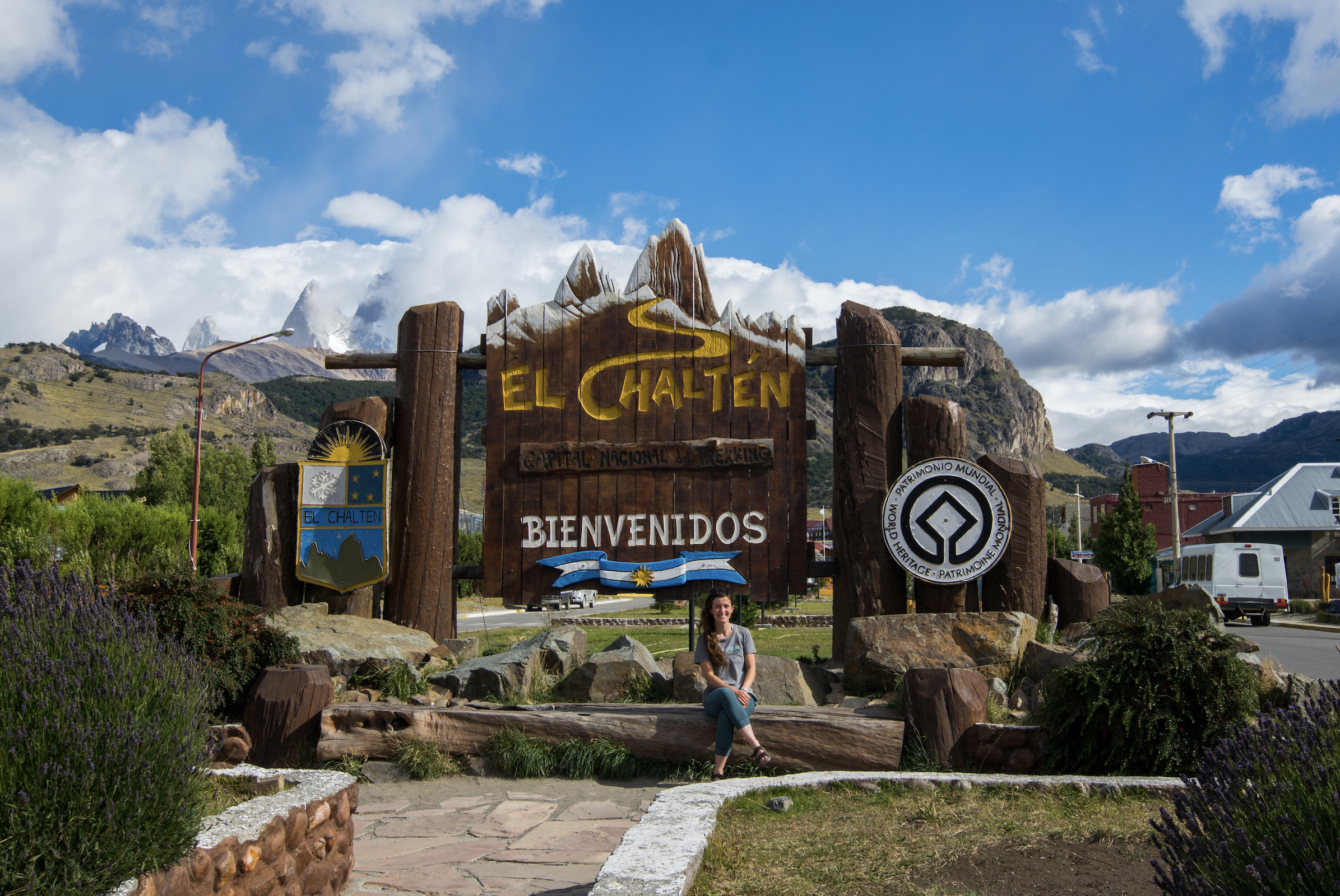 Tourist sitting in front of the El Chaltén town sign