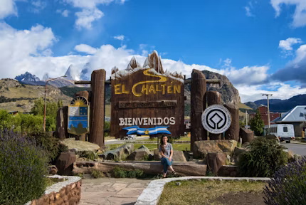 Tourist sitting in front of the El Chaltén town sign