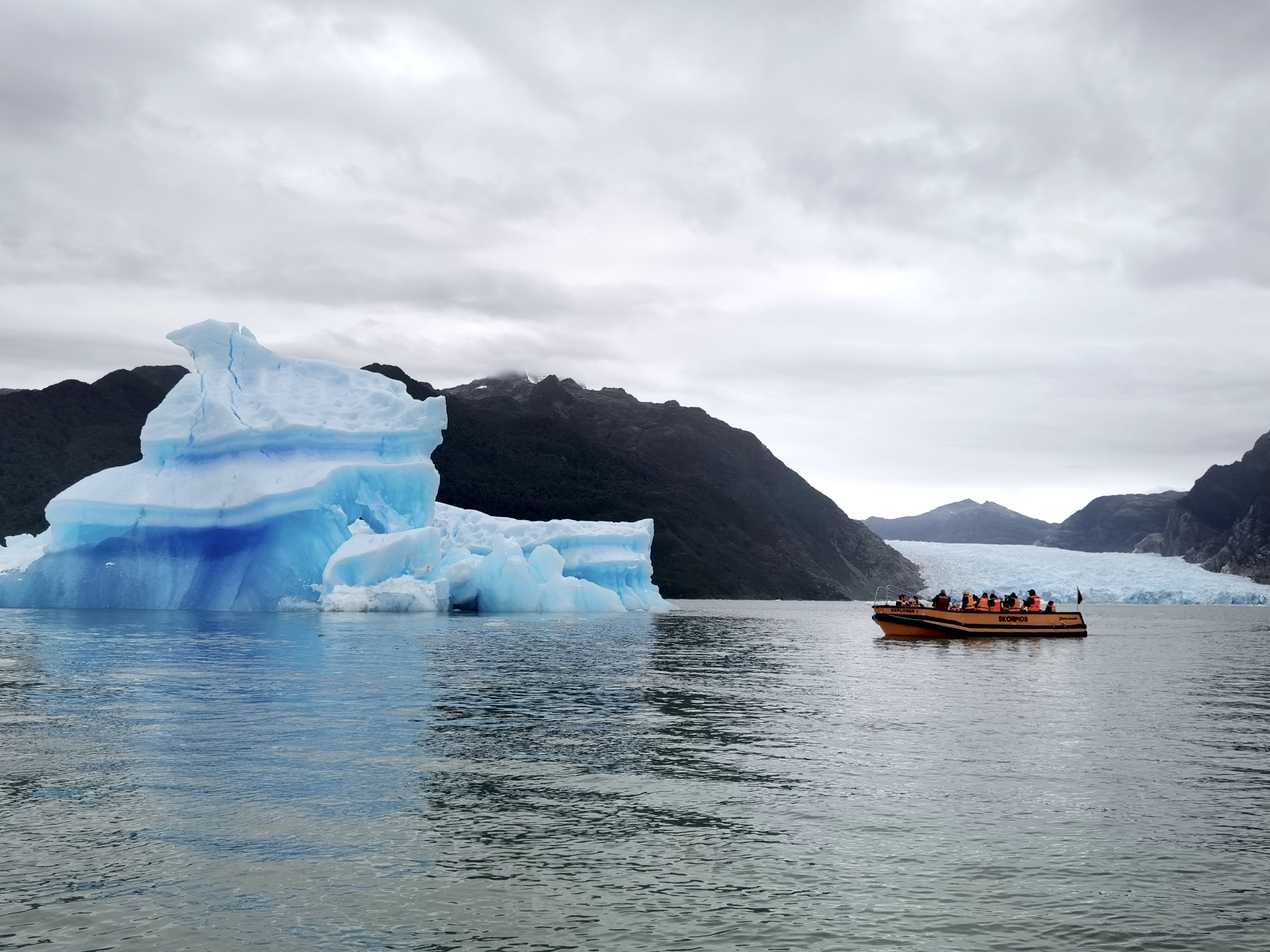 A small tourist boat cruises past an iceberg by the San Rafael Glacier in the northern Chilean Fjords