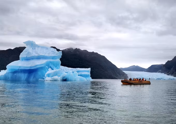 A small tourist boat cruises past an iceberg by the San Rafael Glacier in the northern Chilean Fjords