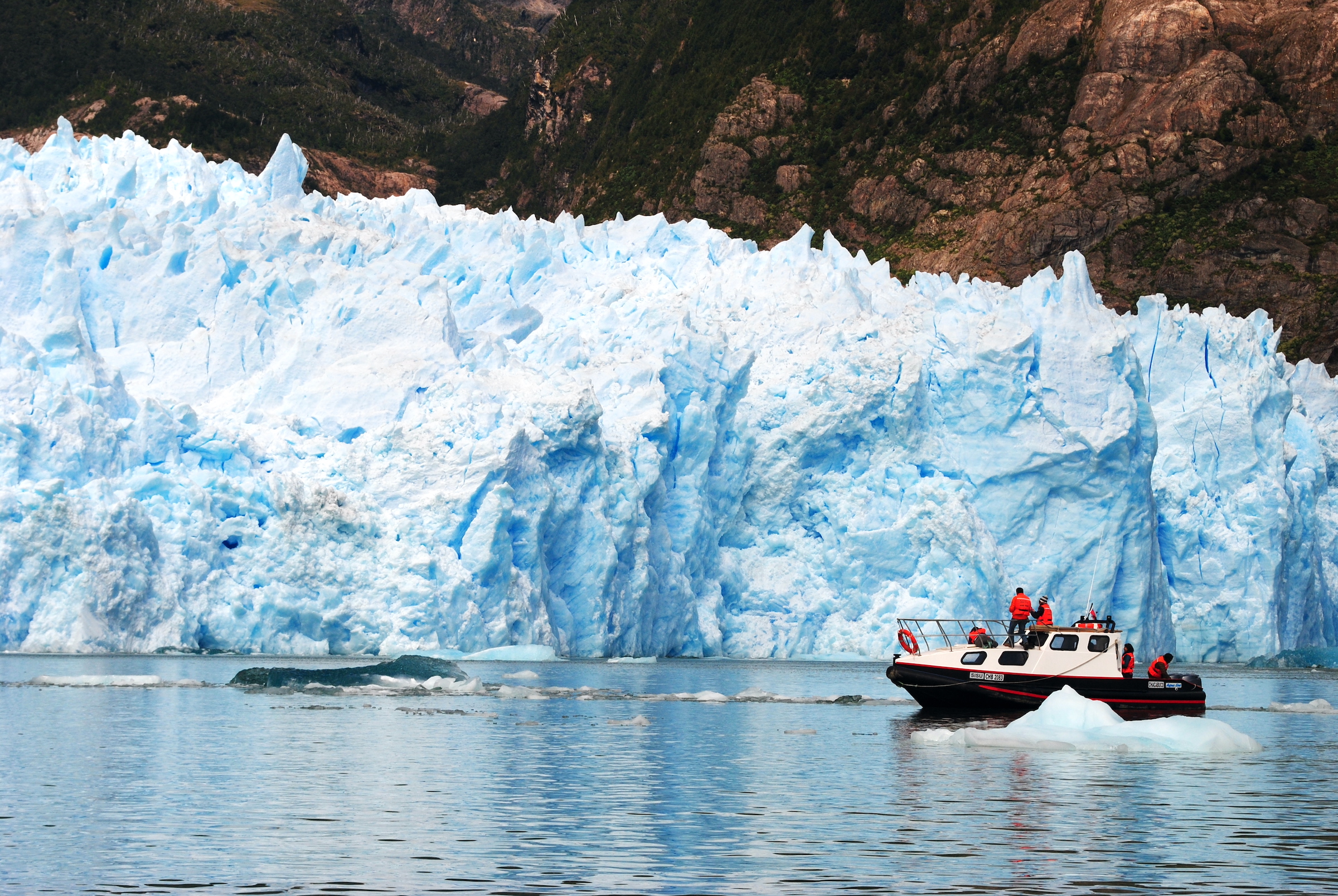 A small boat cruises past the San Rafael glacier in the northern Chilean Fjords