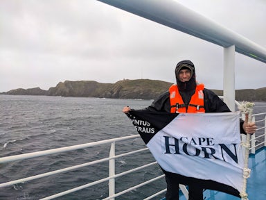 A tourist holds up a Cape Horn flag on an Australis cruise ship in Tierra del Fuego