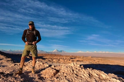 A male hiker standing on a mountain ridge in the Salt Mountains of the Atacama Desert in northern Chile