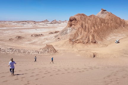 Tiny figures of hikers explore the vast red sandy rocks of Vallecito in Chile's Atacama Desert