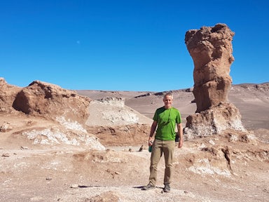 A tourist standing next to rock formations in the Salt Mountains of Vallecito in Chile's Atacama Desert