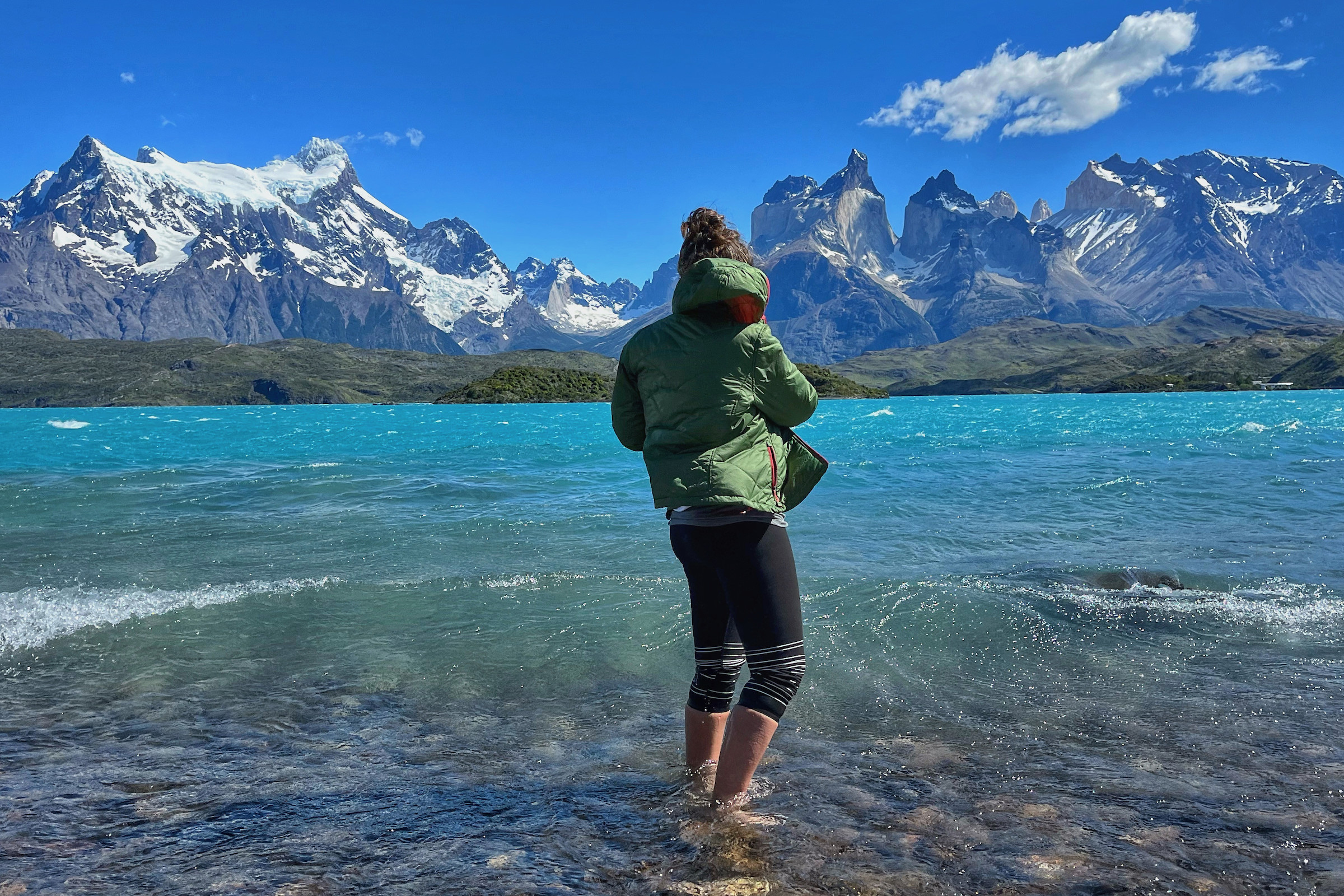 Tourist with feet in lake facing the Cuernos of Torres del Paine