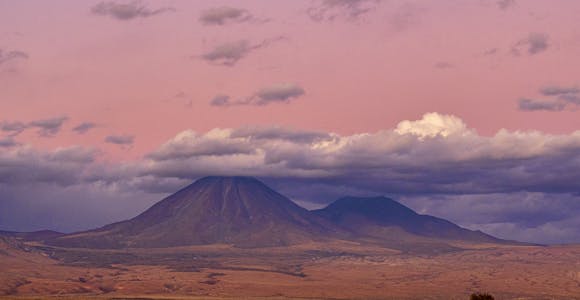 A pink sunset in Chile's Atacama Desert, with the peak of Licanabur volcano surrounded by clouds