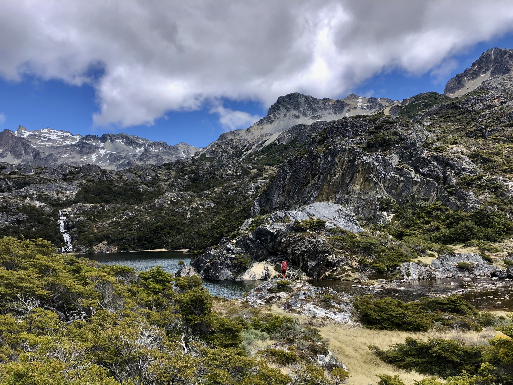 A lone hiker is dwarfed by the wild mountainous landscape of Tierra del Fuego in Patagonia